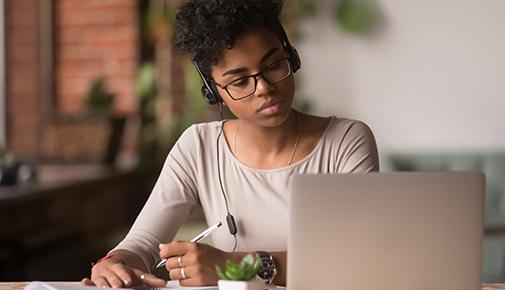 Young woman studying using computer and headphones